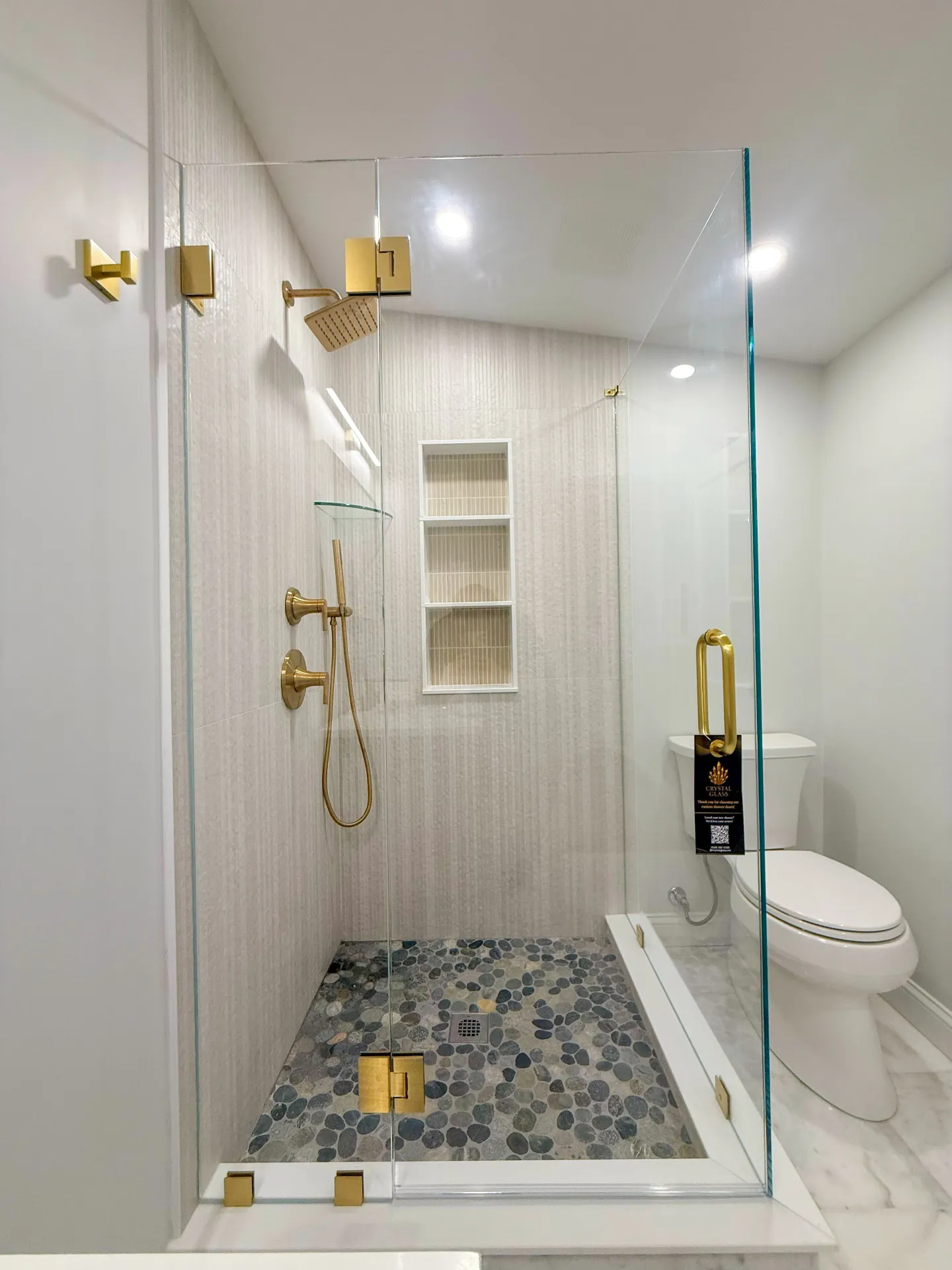 Frameless shower with gold hardware and pebble floor